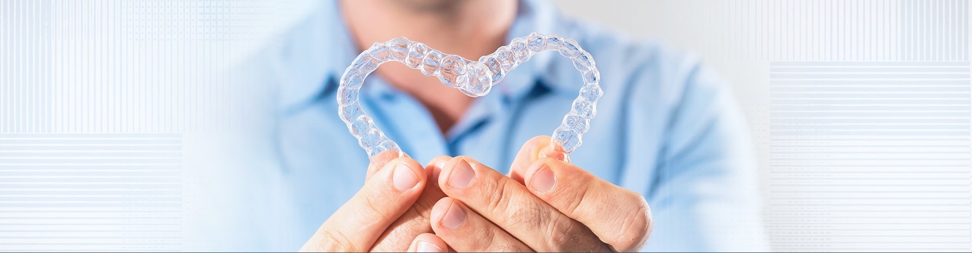 dentist holding up retainers in the shape of a heart